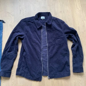 Mörkblå manchester overshirt - Snygg mörkblå overshirt i manchester med dragkedja framtill och klassisk krage. Jackan har en bröstficka och raka ärmar, perfekt att slänga på sig över en hoodie eller t-shirt för en chill look.