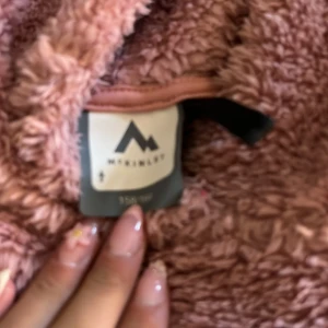 Rosa fluffig hoodie från McKinley - Supermjuk och fluffig rosa hoodie från McKinley med huva och magficka. Perfekt för kyliga dagar när du vill vara både varm och snygg. Långärmad och i mysigt fleece-material som känns som en kram. Hör av dig om du har några frågor💕