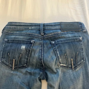 Lågmidjade bootcut jeans - Säljer ett par blå jeans från Fornarina med bootcut-modell och låg midja. Jeansen har slitna detaljer och snygga detaljer på bakfickorna💕
