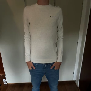 Beige stickad tröja från Bondelid - Snygg beige stickad tröja från Bondelid med diskret broderad logga på bröstet. Tröjan har rund halsringning och långa ärmar, perfekt för en stilren och enkel look. Passar dig som gillar klassisk och clean stil.