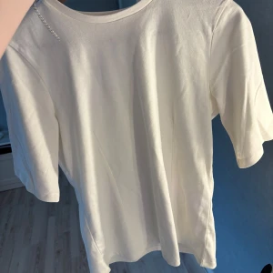 Vit basic t-shirt i bomull - T-shirt med detaljer på magen så tröjan blir mer figursydd! Aldrig använt den är helt ny. Nypris 299
