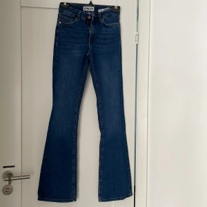 Blå bootcut jeans från ONLY, S/32 - Snygga blå jeans från ONLY i bootcut-modell med klassisk femficksdesign. Jeansen har normal passform, dragkedja och knapp framtill samt bälteshällor. Tillverkade i mjukt denimtyg som sitter skönt hela dagen.