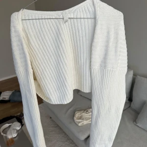 Vit ribbad croppad kofta från H&M - Säljer en vit ribbstickad kofta från H&M i storlek L. Tröjan är croppad med lång ärm och har en snygg, enkel design som passar perfekt till jeans eller kjol. Materialet är mjukt och stretchigt 🤍