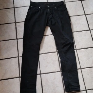 Svarta Nudie jeans - Svarta Nudie jeans i en Slim modell. Storlek W31/L32. Lagade på knät men märks inte av vid användning.