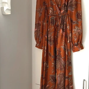 Långklänning med mönster - Ljuvlig klänning med fina detaljer. Transparenta ärmar och knytband i midjan. Jättefint skick finns inget att anmärka på! 