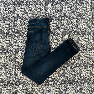 Jack & Jones Slim Fit Jeans - Mörkblå slim fit jeans från Jack & Jones, modell Glenn. Snygg tvätt och klassiska fem fickor. Jeansen har smal passform och är tillverkade i stretchig bomullsdenim för extra komfort. Perfekta för dig som gillar en modern och stilren look. Nypris 900kr, mitt pris 250kr!