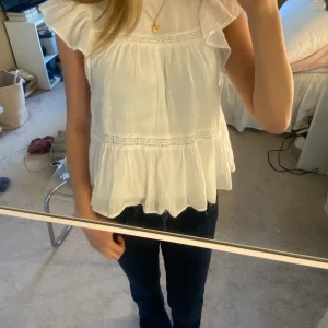 Vit volangblus från Gina Tricot - Supersöt vit blus från Gina Tricot med volangärmar och broderade detaljer. Den är i storlek 134/140 men den passar ändå mig som är ca 167cm.