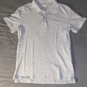 Grå pikétröja med krage, storlek S - Produkt: grå pikétröja från Cubus Storlek: S Nypris: 300 kr Skick: Mycket bra skick (använd få gånger) Färg: grå  Material: bomull  Stil: Stilren / Klassisk / Casual Perfekt för: Vardagsbruk, jobb, festligare tillfällen, sommaroutfits  Beskrivning: Grå piké från Cubus med stilren design, köpt för 300 kr för ett år sedan. Mycket lite använd och i utmärkt skick. Lätt att matcha med både jeans och chinos – perfekt för både avslappnade och mer uppklädda tillfällen. Bekvämt material och hög kvalitet.