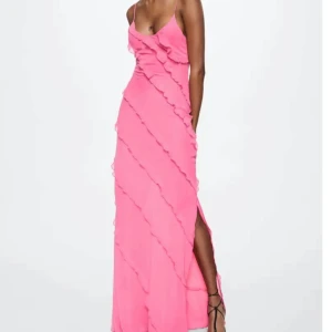 Rosa långklänning med volang  - Säljer en superfin rosa långklänning från mango limited edition  med tunna axelband och v-ringning. Klänningen har diagonala volangdetaljer och en slits på sidan. Materialet är lätt och flowy polyester, perfekt för sommarens alla tillfällen. Dragkedja i sidan