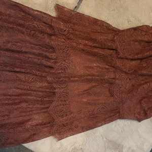 Brun spetsklänning från H&M - Säljer en brun spetskjol från H&M i storlek 40. Klänningen har ett vackert spetsmönster och är fodrad med mjukt tyg. Den har en feminin siluett och passar perfekt för dig som gillar romantiska detaljer och snygg design. Kommer med en topp in o checka profil.