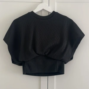 Topp - En jätte snygg svart topp som sitter åt i midjan vilket framhäver kroppsformen och ger en fin passform. Toppen passar perfekt till både vardag och festliga tillfällen.