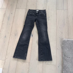 Svarta bootcut jeans Gina Tricot 152 - Snygga svarta jeans från Gina Tricot i storlek 152. Modellen har bootcut-ben och klassisk femficksdesign med coola detaljer på bakfickorna. Jeansen är i stretchigt denimtyg och har en mörk tvätt som passar till allt.