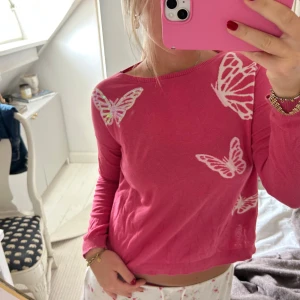 Rosa tröja med fjärilar - Superfin rosa tröja med vita fjärilar som motiv. Tröjan har rund halsringning och långa ärmar🩷🩷