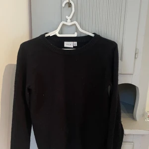 Svart stickad tröja från VILA - En svart stickad tröja från VILA i storlek XS. Tröjan har rund halsringning och långa armar.  Materialet är mjukt och bekvämt.