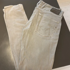Replay Anbass ljusgrå jeans - Säljer ett par Replay Anbass jeans i en snygg ljusgrå färg. W31 L32. Modellen har klassisk femficksdesign, raka ben och diskreta detaljer. Jeansen är tillverkade i mjuk bomull med lite stretch för extra komfort. Perfekta för dig som gillar stilrena och enkla jeans.