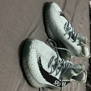 Adidas Yeezy Boost 350 V2 Blå salt - Säljer ett par Adidas Yeezy Boost 350 V2 i ljusblått med svart rand och SPLY-350-tryck på sidan. Skorna har stickad ovandel, snörning och en genomskinlig, ribbad sula. Perfekta för dig som gillar streetwear och vill sticka ut med en unik färg. Pris kan diskuteras skorna kommer utan box