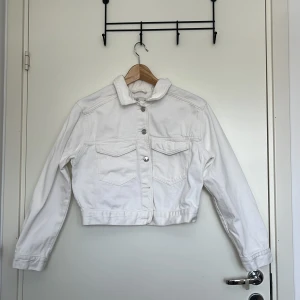 Vit jeansjacka från Gina Tricot XS - Vit jeansjacka från Gina Tricot i storlek XS. Klassisk modell med två bröstfickor med lock, silvriga knappar och krage. Jackan är croppad och har långa ärmar, inga missfärgningar.