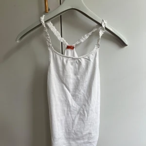 Fint Linne - Söt vit linnetopp från Tape à l'Oeil med smala volangprydda axelband och racerback-detalj. Toppen är i mjuk bomull.