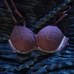 Victoria's Secret bh - Storlek 65A. Snygg lila bh med vadderade kupor och spetsdetaljer. Axelbandslös design med avtagbara axelband och mjuk kant i satin. 