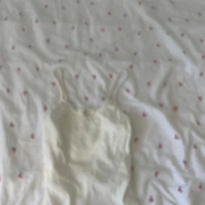 Vit ribbad linnetopp från H&M - Säljer en enkel och fräsch vit ribbad linnetopp från H&M. Toppen har smala axelband och är tillverkad i ett mjukt, stretchigt material som sitter skönt på kroppen. Perfekt att matcha med jeans eller kjol för en clean look.