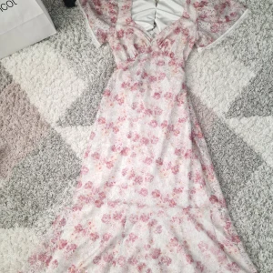 Blommig långklänning med spets och öppen rygg - Superfin långklänning från DRY LAKE  med blommigt mönster i rosa och beige toner. Klänningen har spetsdetaljer, v-ringning, korta ärmar och en snygg öppen rygg. Finns bara ett enda exemplar, priset kan diskuteras och skriv om du vill ha fler bilder 