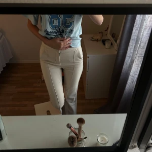 Beige lågmidjade kostymbyxor - Snygga beige kostymbyxor med lågmidja och raka ben. Byxorna har markerade sömmar framtill som ger en clean och modern look. Passar perfekt till en chill t-shirt eller en dressad topp. Materialet känns mjukt och har lite stretch för extra komfort.