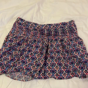 Blommig kortkjol från Zara - Supersöt kortkjol från Zara med blommigt mönster i blått, rosa och vitt. Kjolen har smockad midja och dragkedja i sidan för enkel påklädning. Perfekt för vår och sommar när du vill ha en färgglad och luftig look. Den går ej att köpa längre i Zaras butik eller på hemsidan! Pris och frakt kan diskuteras 