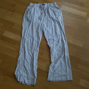 Beiga linnebyxor med snörning lager 157 - Luftiga beiga linnebyxor från lager 157 med elastisk midja och snörning. Byxorna har raka ben, sidfickor och en bakficka. Du står för frakten, vid mer info skriv 