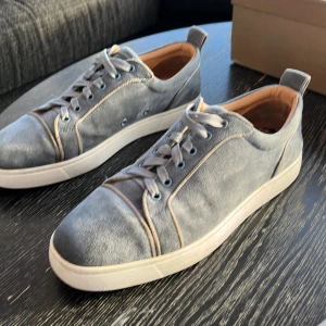 Grå/blå sneakers från Christian Louboutin - Snygga grå sneakers från Christian Louboutin med den ikoniska röda sulan. Skick 8/10 lite slitna vid hälarna på båda skorna men annars i bra skick.   Bara att fråga om fler bilder obs skorna ser gråa ut men är mer mot det blåa hållet