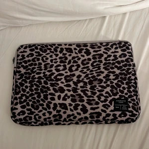 Leopardmönstrad datorväska lager 157 - Snygg datorväska från lager 157 med leopardmönster i svart och beige. Väskan har dragkedja och är tillverkad i tåligt tyg, perfekt för att skydda din laptop. Stilsäker accessoar som sticker ut i plugget eller på jobbet.