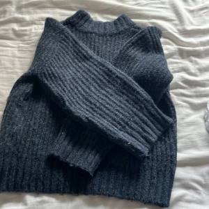 Mörkblå ribbstickad tröja - Säljer en mörkblå ribbstickad tröja med hög hals och långa ärmar. Tröjan är grovstickad och har en chill, loose passform som är perfekt för kalla dagar. Materialet känns mjukt och värmande, och färgen är riktigt snygg och enkel att matcha.