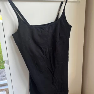 Svart linne - Basic svart linne. Tillverkad i mjuk bomull med lite stretch för extra komfort. Perfekt för dig som gillar minimalistisk stil och vill ha något som är lätt att matcha.