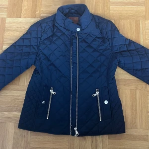 Mörkblå quiltad jacka från Zara  - Säljer en mörkblå quiltad jacka från Zara Girls i storlek 140. Insidan är fodrad med ett stjärnmönstrat tyg. Den har tecken på användning men bara på insidan så det är inget som märks!