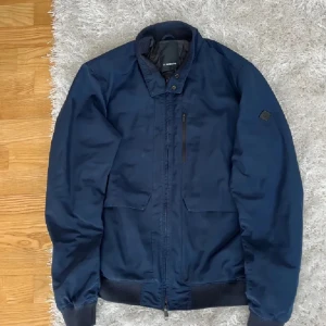  J.Lindeberg Jacka - Säljer en stilren marinblå bomberjacka från J.Lindeberg. Jackan är i 10/10 skick, nästan aldrig använd och storlek M. Passar någon mellan 160-170 cm och 60-70kg😇😇😇