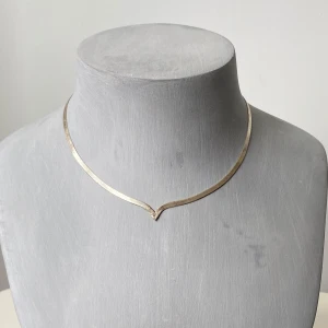 Tunt V-format halsband i silver - Säljer ett elegant och tunt halsband i äkta silver med V-formad front. Halsbandet har en platt kedja och stängs med ett klassiskt klolås. Märkt med 925-stämpel för sterlingsilver.