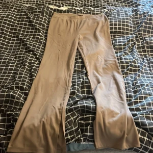 Beiga utsvängda byxor från 157 - Säljer ett par beiga byxor från Lager 157 i storlek XL. Byxorna har en utsvängd passform och är tillverkade i ett mjukt, stretchigt material som ger en bekväm känsla. Perfekta för dig som gillar en stilren och enkel look.