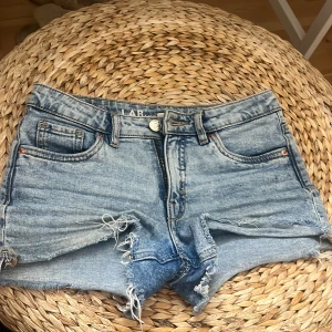 Ljusblå jeansshorts - Ljusblå jeansshorts med råa fransade kanter och slitningar framtill. Klassisk femficksmodell med knapp och dragkedja. Perfekta för sommaren och har en avslappnad, trendig look.🌟🙌🏼