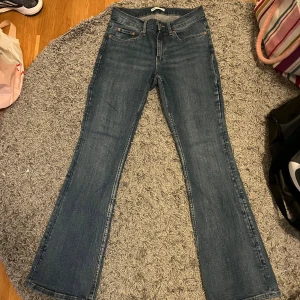 Blå bootcut lågmidjade jeans  - Säljer ett par klassiska blå bootcut jeans med fem fickor och normal passform. Jeansen har en lätt utsvängd benslut och är tillverkade i denim. Knappast använda 