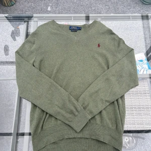 Grön Polo Ralph Lauren-tröja – Pima Cotton, strl L - Mjuk och stilren tröja från Polo Ralph Lauren i exklusiv Pima Cotton. Snygg grön nyans, v-ringad och med ikoniska loggan på bröstet. Perfekt layering-plagg för både vardag och mer dressade looks. Skön, tidlös och i riktigt fint skick!