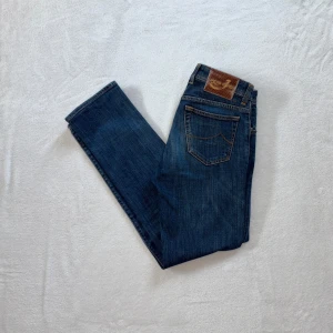 Blå jeans från Jacob Cohën - Säljer ett par klassiska blå jeans från Jacob Cohën i modell med raka ben och normal passform. Jeansen har fem fickor och hästskinnpatch bak i midjan. Medium W31. (OBS, insidan på framfickorna är i dåligt skick, men kan lätt lagas). Har du några funderingar eller liknande så är du mer än välkommen att ställa frågor!