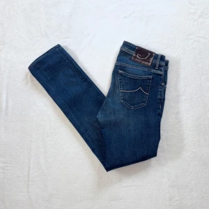 Mörkblå jeans från Jacob Cohën - Säljer ett par klassiska mörkblå jeans från Jacob Cohën. Jeansen har raka ben, femficksmodell och snygga kontrastsömmar. Hästskinnspatch baktill i midjan och diskret tvätt. Medium W32. Har du några frågor eller funderingar så är du mer än välkommen att fråga!