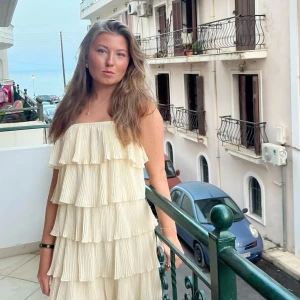 Plisserad klänning med volanger - Säljer en ljusgul plisserad klänning med flera lager volanger💕Klänningen har en luftig och flowy känsla, perfekt för sommaren!!