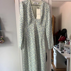 Adoore klänning  - Superfin långklänning från Adoore med ljus botten och blått blommönster. Klänningen har v-ringning, långa ärmar och slutar typ på vaden. Perfekt för vår och sommar! Säljer för den va för liten och kunde inte lämna tillbaka. Har S i vanliga fall och det va några knappar ifrån att kunna stänga så skulle säga att den passar XS. Pris går att diskutera vid snabb affär. 