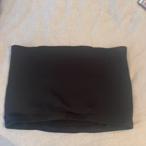 Svart tubtopp - Säljer en enkel svart tubtopp som är perfekt att matcha med olika outfits. Toppen är ärmlös och har en tight passform som sitter snyggt på kroppen. Passar bra till sommaren eller när du vill ha en stilren bas i garderoben.