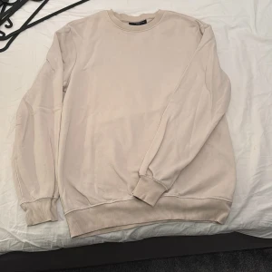 Beige crewneck sweatshirt från H&M - Säljer en beige crewneck sweatshirt från H&M i relaxed fit. Tröjan har långa ärmar, rund halsringning och breda ribbade muddar vid ärmslut och nederkant. Perfekt för en avslappnad stil.