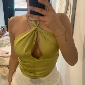 Grön omlott halterneck topp - Snygg grön halterneck topp med omlott och knyt i ryggen. Toppen har en twistad detalj framtill och är croppad med öppen rygg. Perfekt för dig som vill sticka ut med en trendig och elegant look.