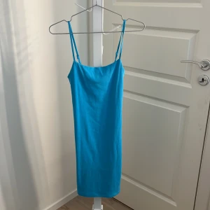 Blå kortklänning med smala axelband från Bik Bok - Säljer en enkel och stilren blå kortklänning från Bik Bok. Klänningen har smala axelband och rak passform, perfekt för varma dagar. Materialet känns mjukt och stretchigt.💙