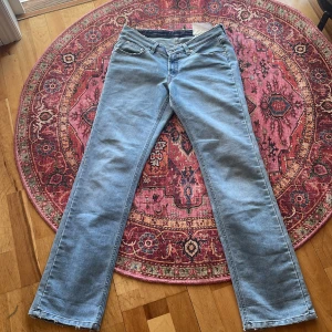 Blå jeansbyxor från Filippa K - Säljer ett par klassiska blå jeansbyxor från Filippa K med raka ben och råa kanter nertill. Byxorna har fem fickor och lite slitna detaljer. De är tillverkade i en bomulls- och polyestermix. Perfekta för en avslappnad och stilren look. Köpte byxorna för ca 2000 tusen från deras hemsida. I Storlek 32/34. Skriv om du har frågor 💕