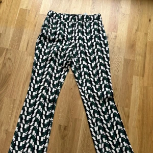 Mönstrade byxor från Zara Basic - Säljer ett par unika byxor från Zara Basic med grafiskt mönster i grönt, svart och vitt. Byxorna har normal passform och raka ben, perfekta för dig som vill sticka ut med din stil. Typ oanvända, köpta på Zara i Miami!