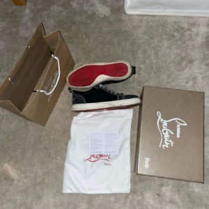 Christian Louboutin - Säljer ett par svarta skor från Christian Louboutin med vita snören och kontrastsömmar. Skorna har den klassiska röda sulan och vita detaljer runt sulan. Kommer med originalkartong, dustbag och påse. ÄR ÖPPEN FÖR BYTEN OCH PRISET ÄR FÖRHANDLINGS BART!
